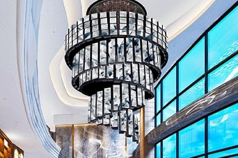 Intérieur du hall de l’hôtel de luxe avec un grand lustre en cristal, des murs en marbre et de grandes baies vitrées, architecture et design modernes.