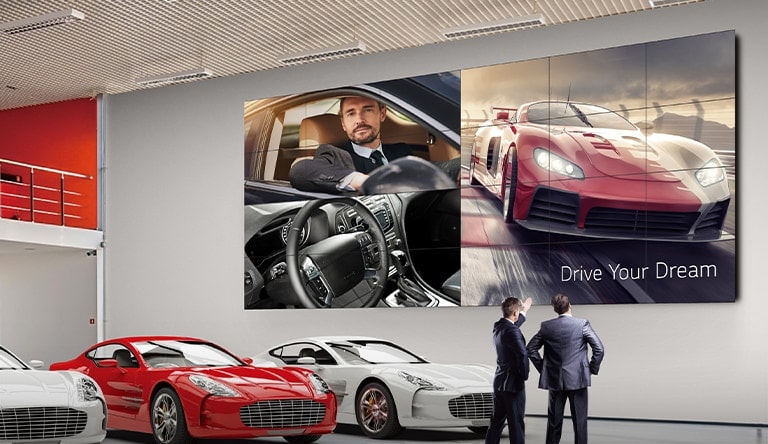 Un grand mur d'images est installé sur le mur du showroom automobile et la publicité d’une voiture est diffusée à l’écran.