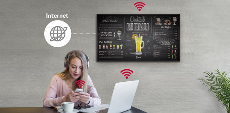 La série UR3J est installée au mur et une femme utilise un PC personnel et un téléphone portable. Cette image montre que l’affichage peut être connecté sans fil à l’ordinateur et au téléphone portable qu’elle tient.
