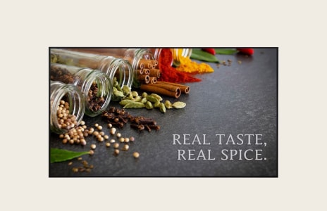 Assortiment d’épices renversant des pots en verre avec des bâtonnets de cannelle, de la cardamome, de la poudre de piment et des herbes affichées sur un fond sombre avec le texte « VRAI GOÛT, VRAI ÉPICE ». – parfait pour la photographie culinaire ou la publicité d’épices.