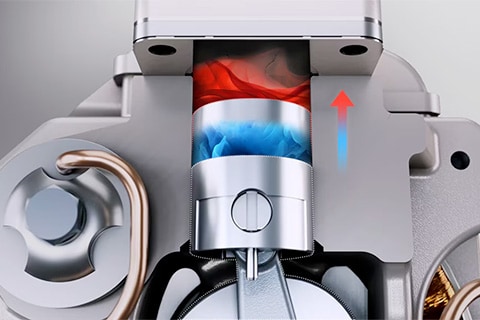 Close-up of a mechanical piston moving upward, showing blue and red airflow representing cooling and heating inside the chamber.