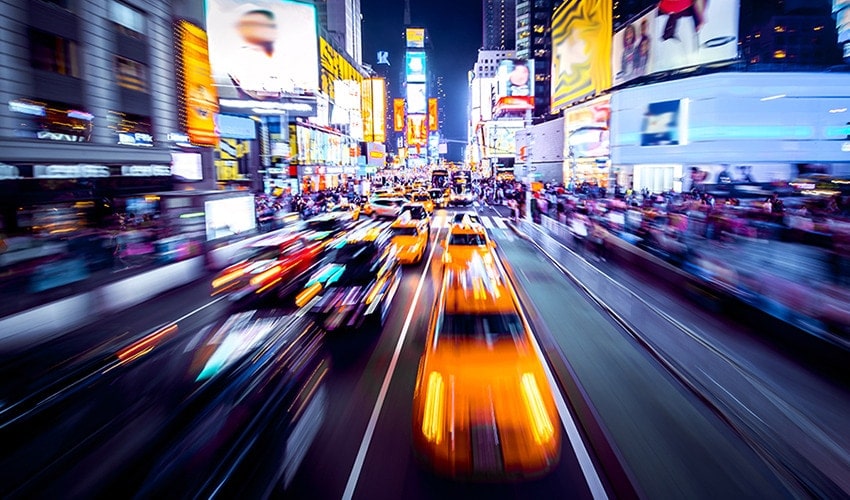 Cars rushing by the advertisements illuminating the city