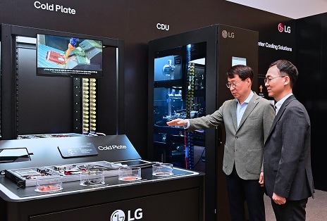 Two executives discussing cooling solutions next to a Cold Plate technology display at an LG exhibition booth.