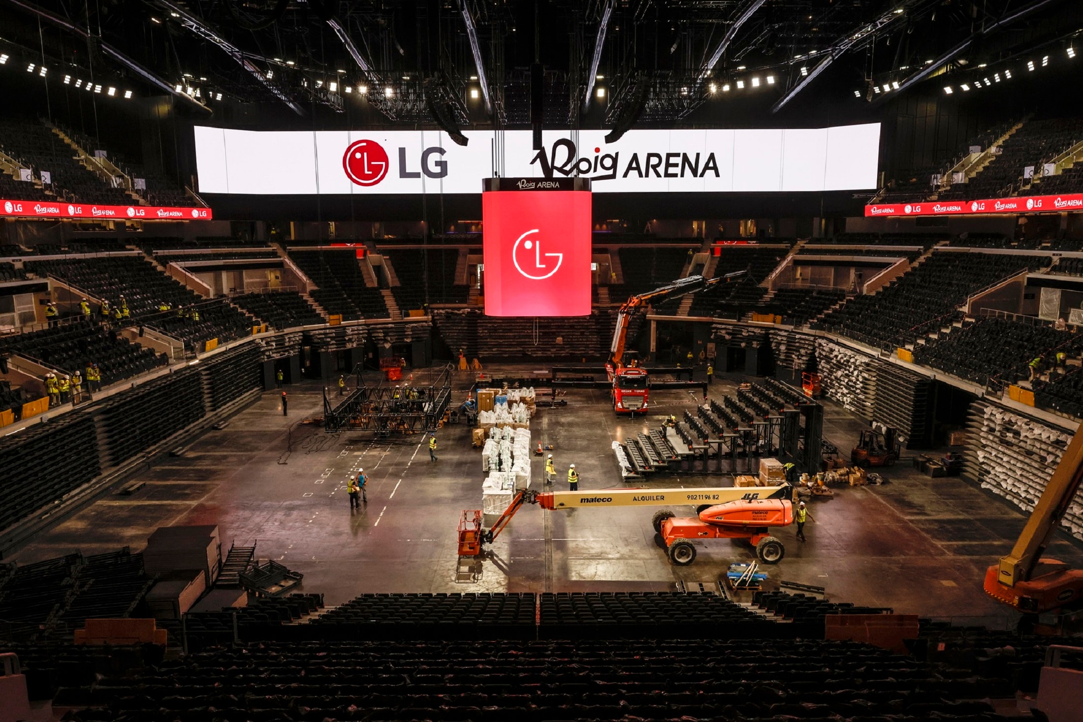 Interior view of Roig Arena under construction with workers and equipment, showcasing large LG LED displays being installed across the stadium