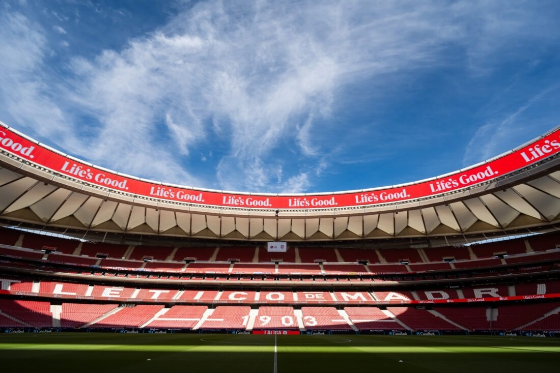 LG delivers a massive ribbon LED board installation at Atlético de Madrid’s football stadium, showcasing advanced mesh LED technology. The panoramic display wraps around the stands with vibrant “Life’s Good” branding under a clear blue sky.