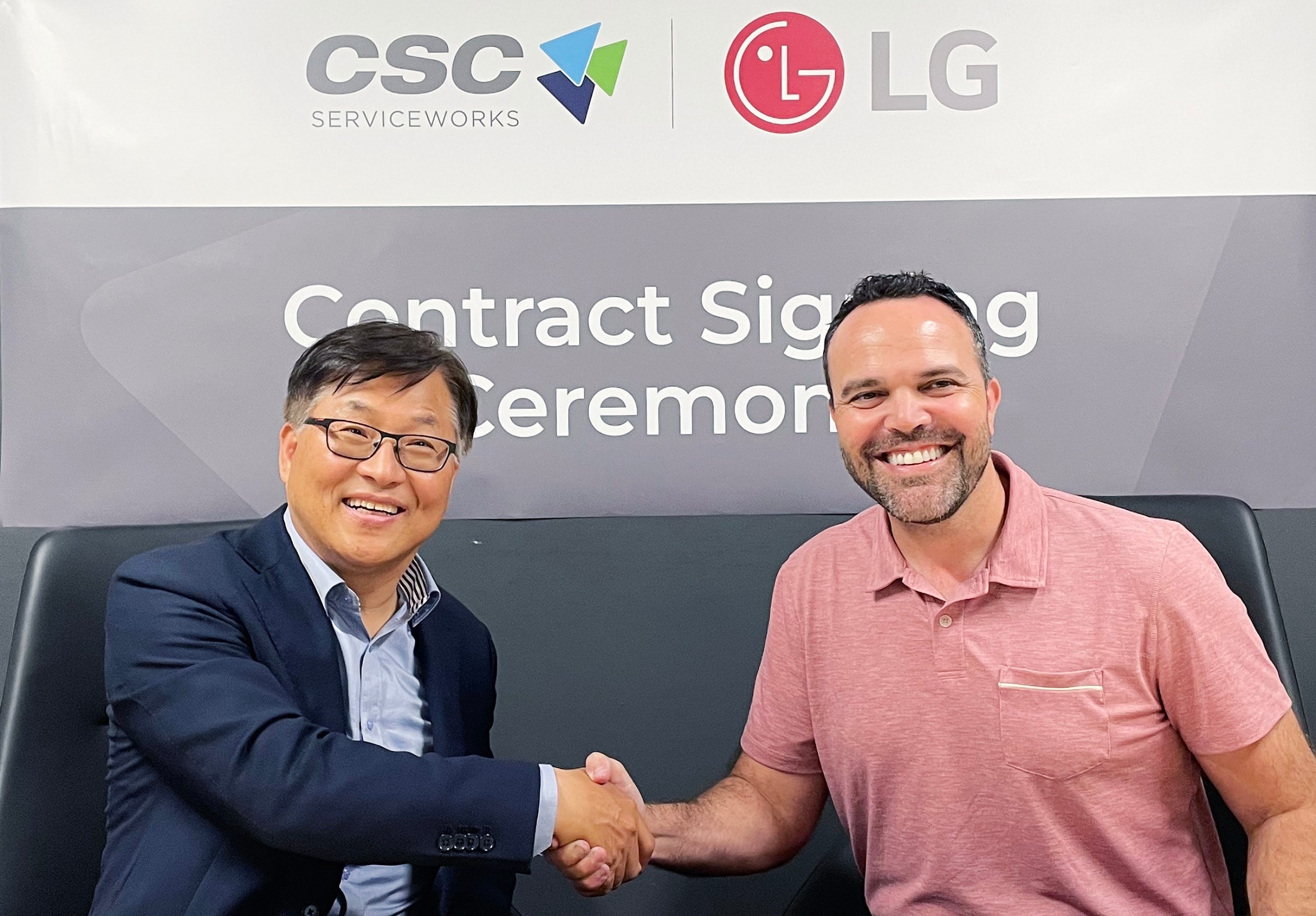 Two business professionals shaking hands and smiling during a contract signing ceremony.
