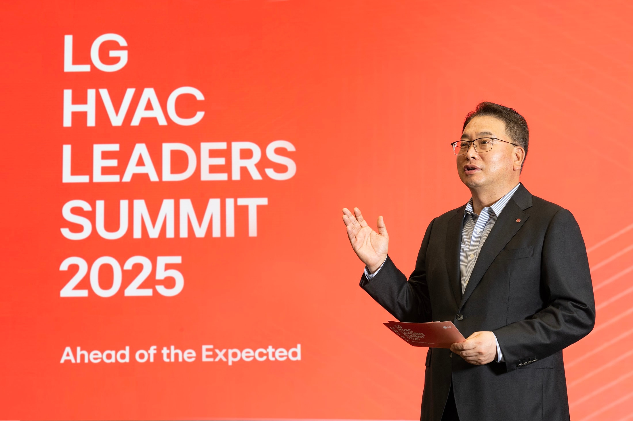 Business professional delivering a speech at the LG HVAC Leaders Summit 2025 with a red event backdrop.