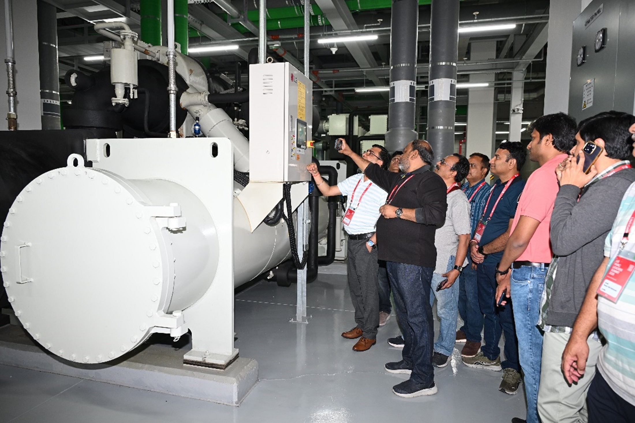 Delegates touring an HVAC facility and inspecting large industrial equipment.
