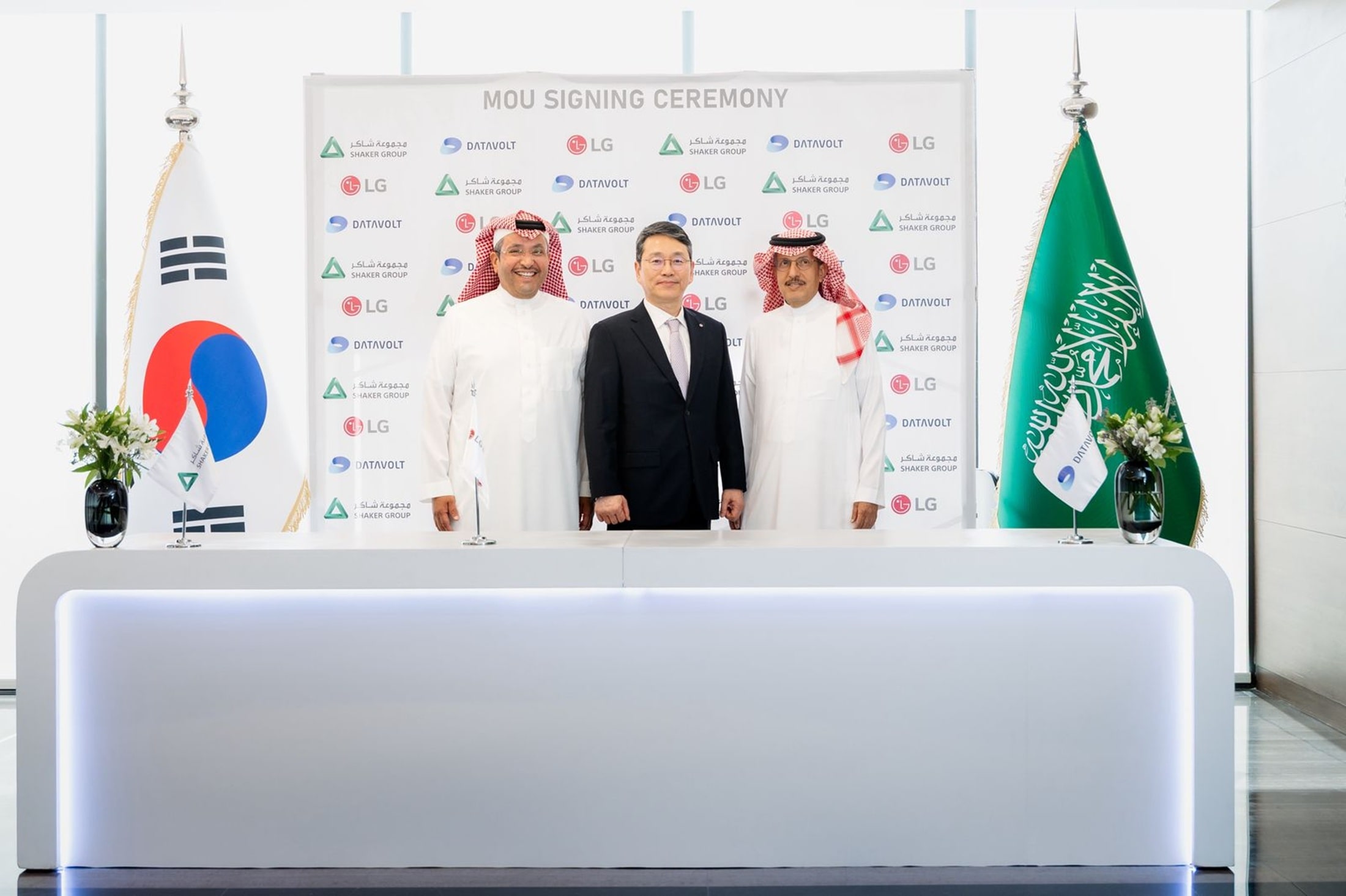 Three executives from South Korea and Saudi Arabia pose together in front of a backdrop with logos during an MOU signing ceremony, with the South Korean and Saudi Arabian national flags displayed on each side