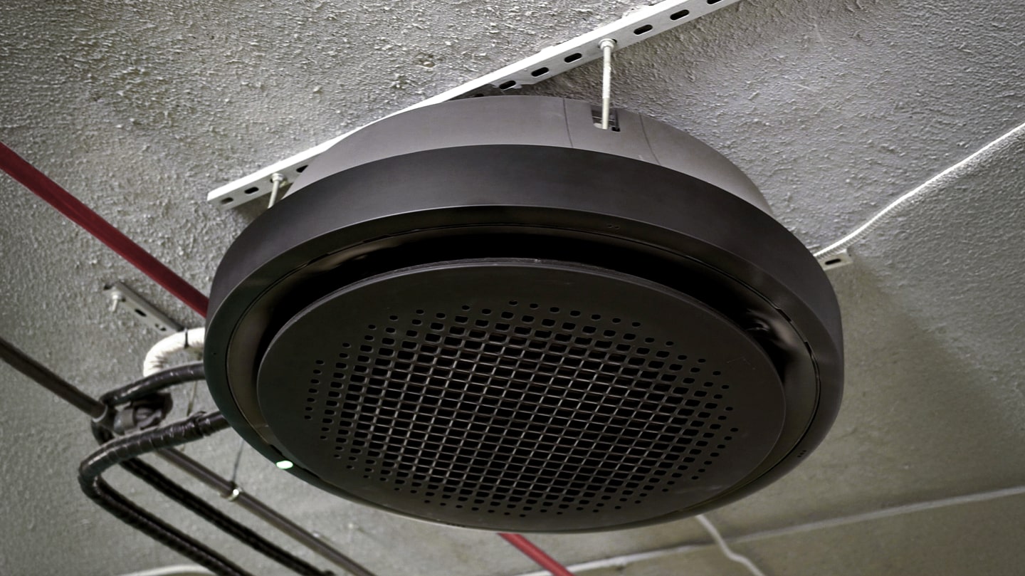 Ceiling-mounted circular air ventilation unit integrated into industrial HVAC system with exposed piping