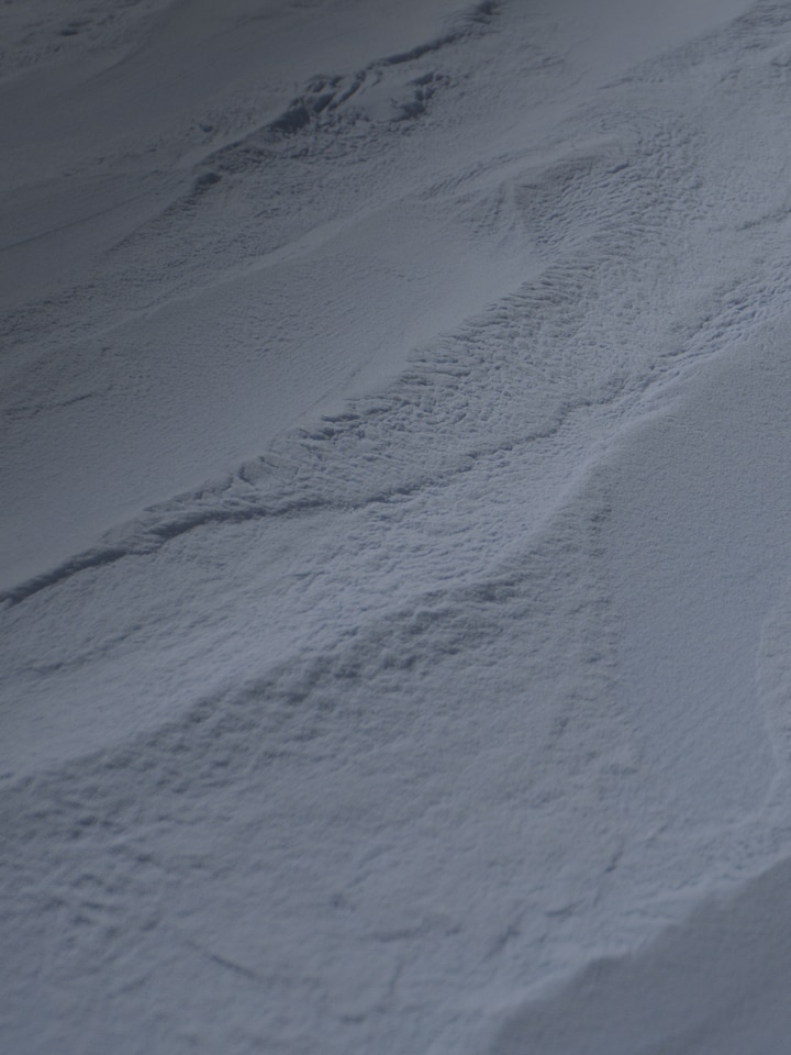 Close-up of a fine powder surface with textured ridges and shadows, resembling industrial or chemical material.