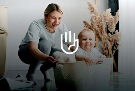 Smiling mother with baby holding laundry basket