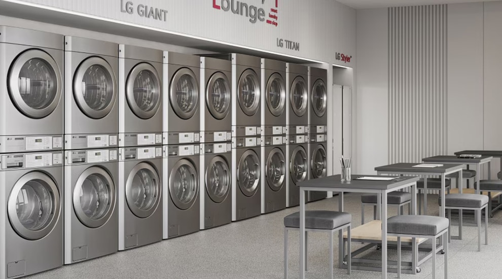 LG Laundry Lounge with multiple rows of stacked commercial washers and dryers in silver finish, tables and chairs arranged for customers