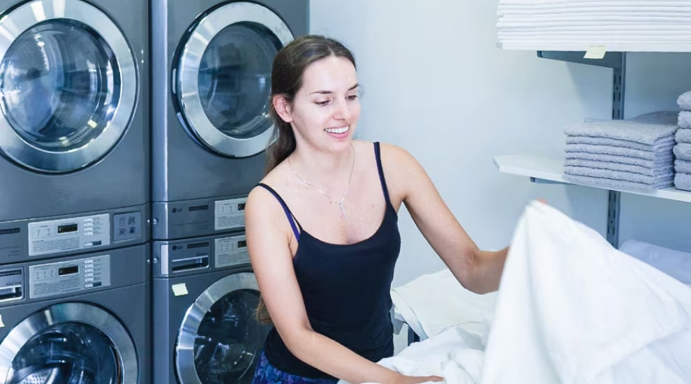 Woman folding laundry in front of LG commercial washers and dryers