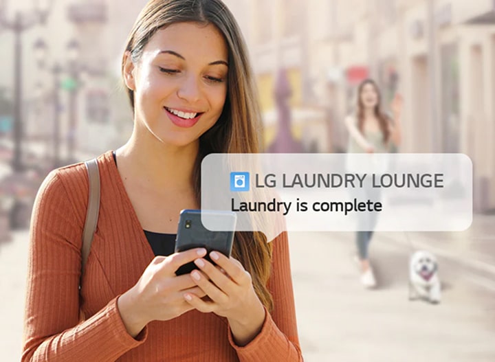 Young woman receiving LG Smart Laundry Lounge notification on her smartphone that laundry is complete, highlighting convenience, mobility, and smart monitoring features.