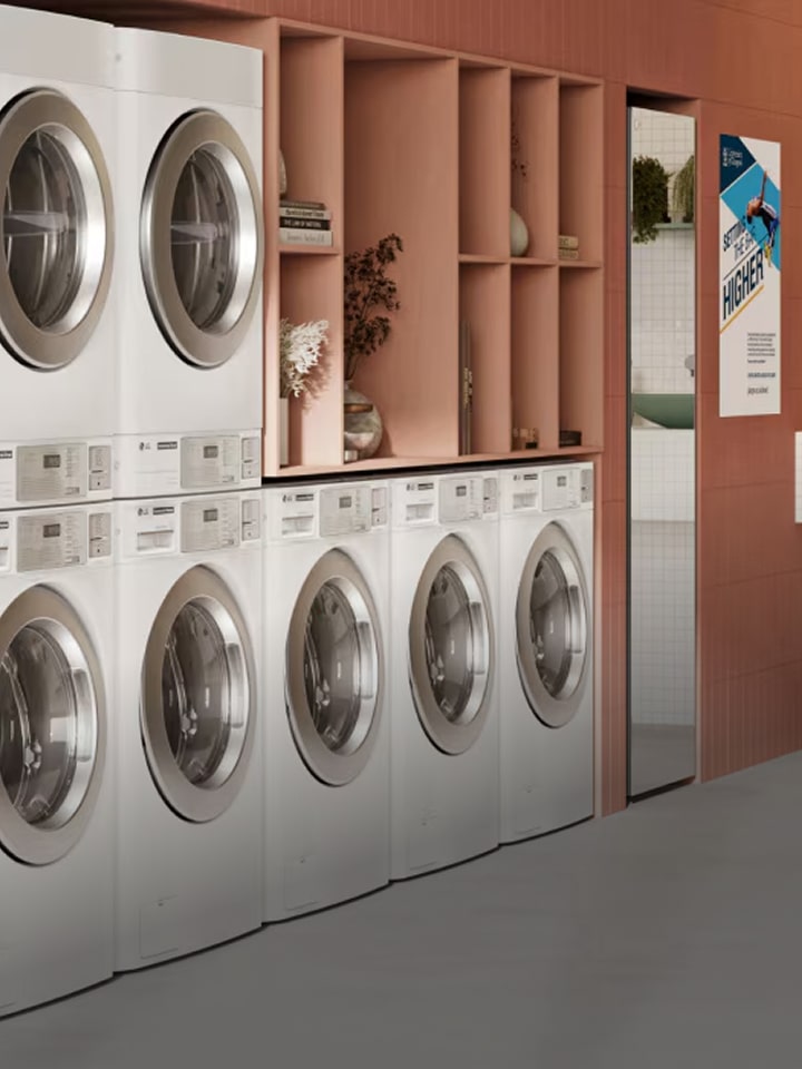 LG Smart Laundry Lounge interior with stacked white washing machines and modern counter space. Stylish, efficient commercial laundry solution designed to enhance business success.
