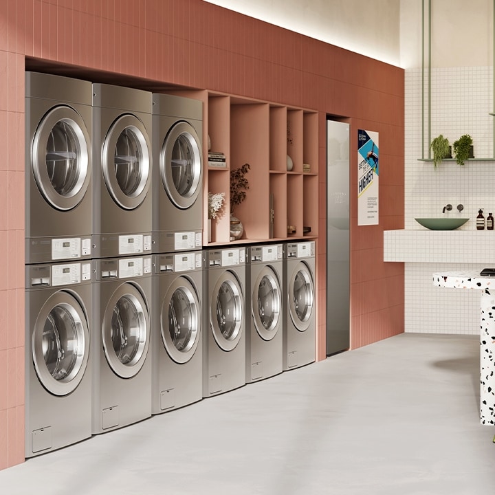 Modern laundromat with rows of LG commercial washers and dryers, laundry carts, and folding tables