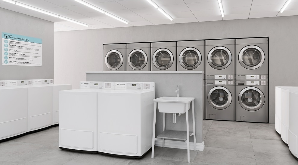 Row of LG commercial front-load washers with payment systems installed in a tiled laundry room