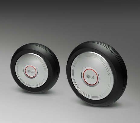 Two LG wheel drive units with circular metal centers and black outer rings shown side by side on a neutral background