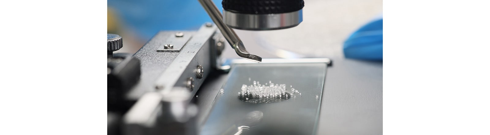 A zoomed-in tip of a microscope that is looking down on glass-like particles.
