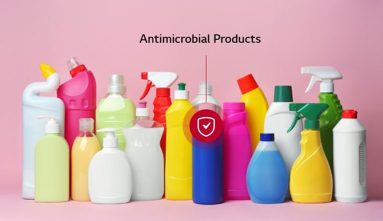 Assorted antimicrobial household cleaning product bottles in various shapes and bright colors, arranged against a pink background