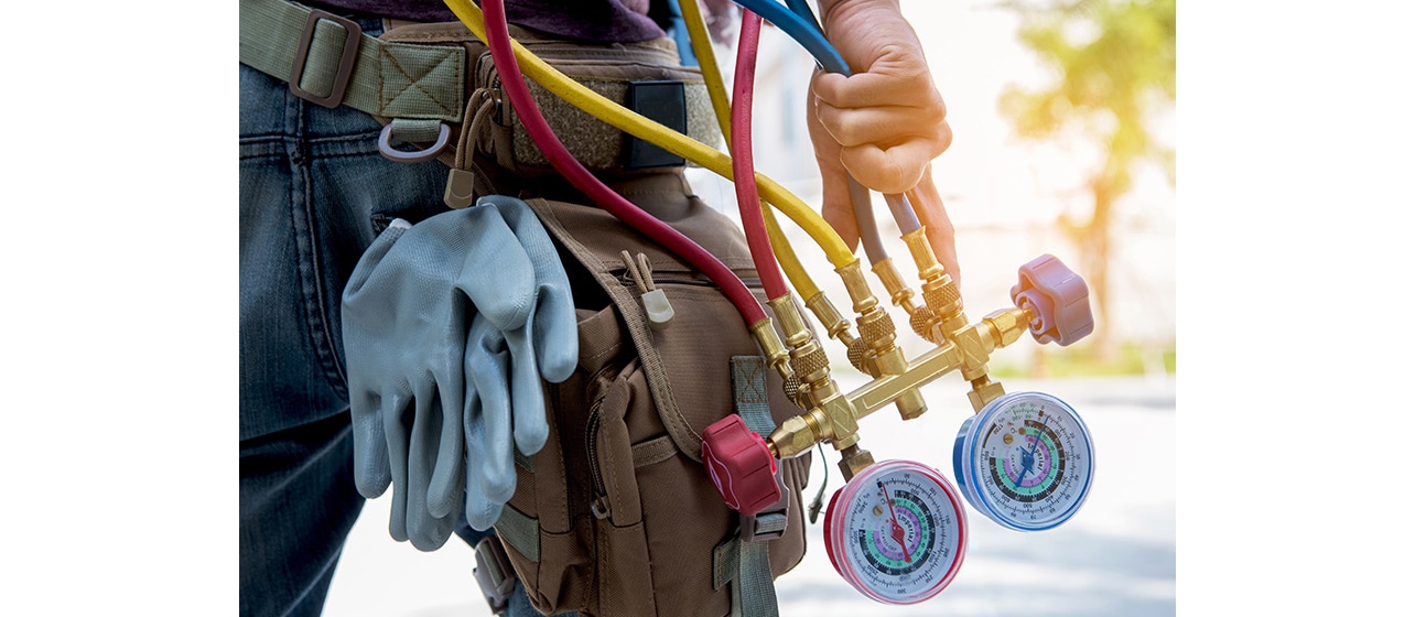 An air conditioner installer is carrying the refrigerant charging device