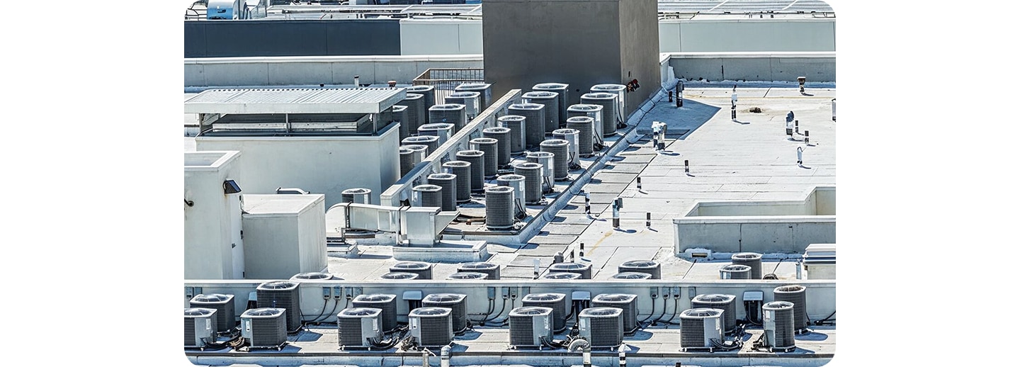 A wide shot of a building rooftop covered with numerous commercial outdoor HVAC units, illustrating large-scale industrial or commercial cooling applications.