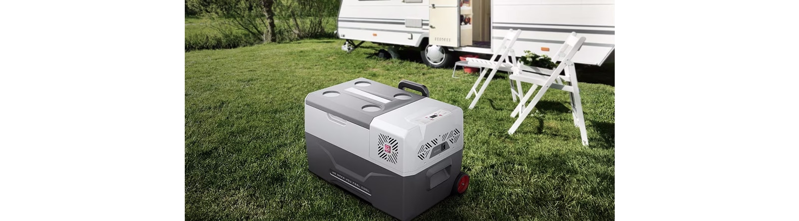 A sleek portable refrigerator in a shade of gray sits prominently beside a camper van, ready for outdoor activities.
