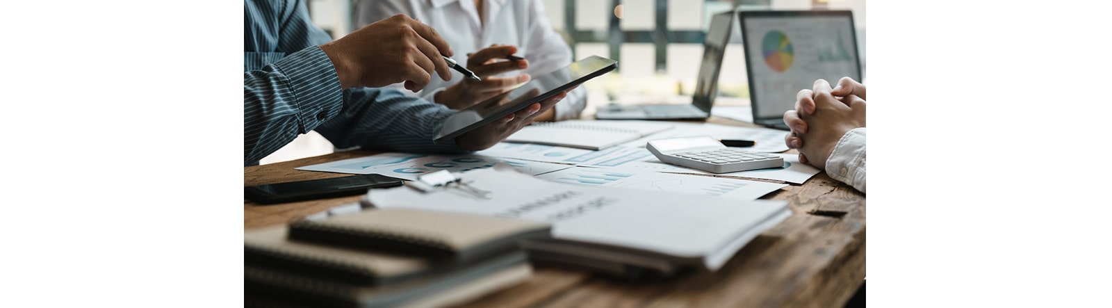 A picture of people having meeting,notes and laptops on the table