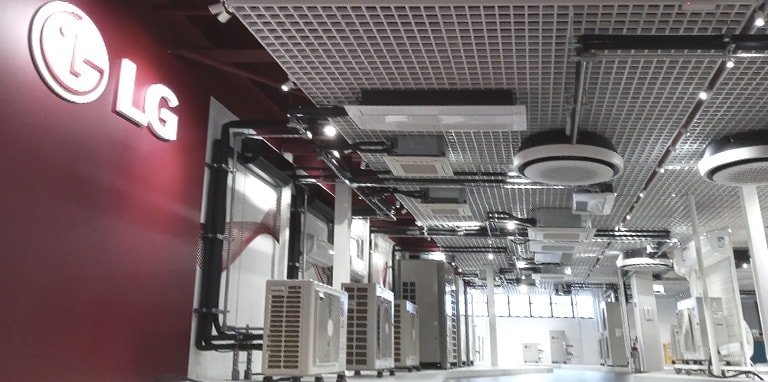 In a showroom-like space, a large LG logo graces the left wall while a series of LG indoor and outdoor units punctuate the ceiling and floor.