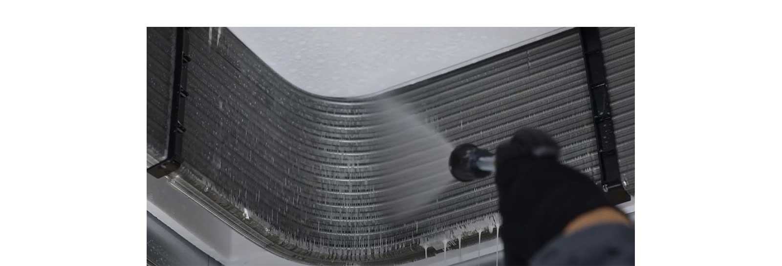 Close-up of LG HVAC coil cleaning process showing technician spraying condenser fins. Symbolizes thorough system maintenance ensuring efficiency and longevity of LG air conditioning units