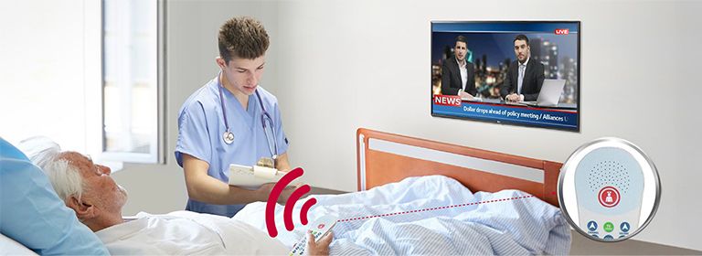 A patient lying in the bed is controlling the TV through a pillow speaker connected to the LN662M.