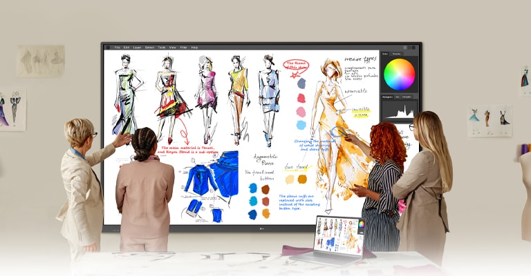 In a studio workspace, a group collaborates by writing directly onto a large wall-mounted smart whiteboard during a discussion.