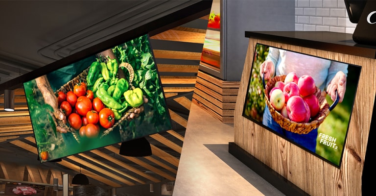 One UL5Q-E is installed on the store ceiling with a down tilt, and the other is mounted below the counter with an up tilt, both displaying content.