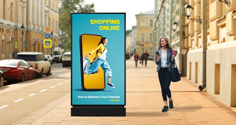 A display as tall as a person is installed on the street, and a woman walking by is watching an advertisement with clear image quality on its screen.