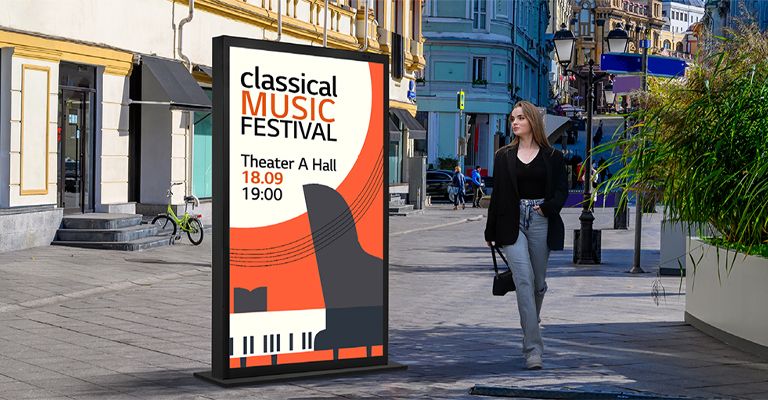 A large-sized display is installed on the street, and a woman is looking at a vivid-quality advertisement on the screen.