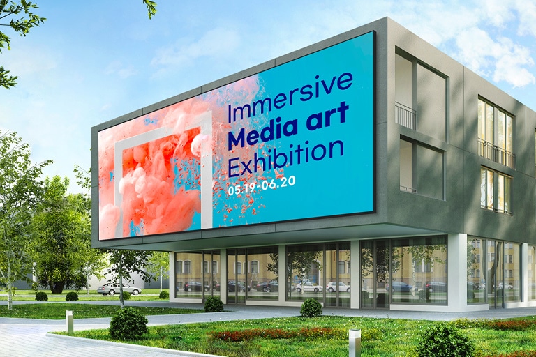 A large LED screen is installed on the exterior wall of the building entrance. Even in strong sunlight, the screen’s content is clearly visible.