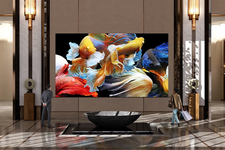 In a spacious lobby, a massive LG MAGNIT shows a vivid underwater scene with colorful fish swimming across the screen.