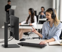 A woman is wearing a headset and working while looking at a monitor.	