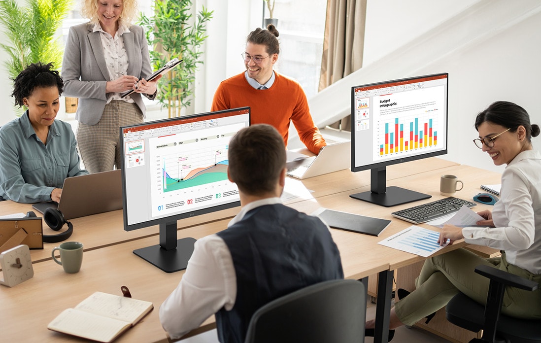 Employees sitting at office desks and having a conversation.