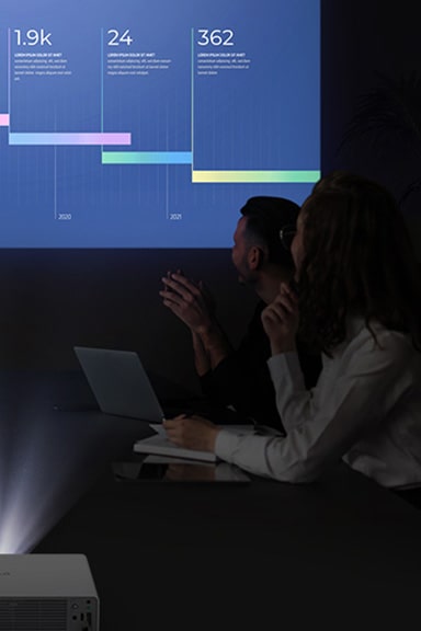 Five people are having a meeting in a dark room, viewing a vibrant display with the LG ProBeam projector.