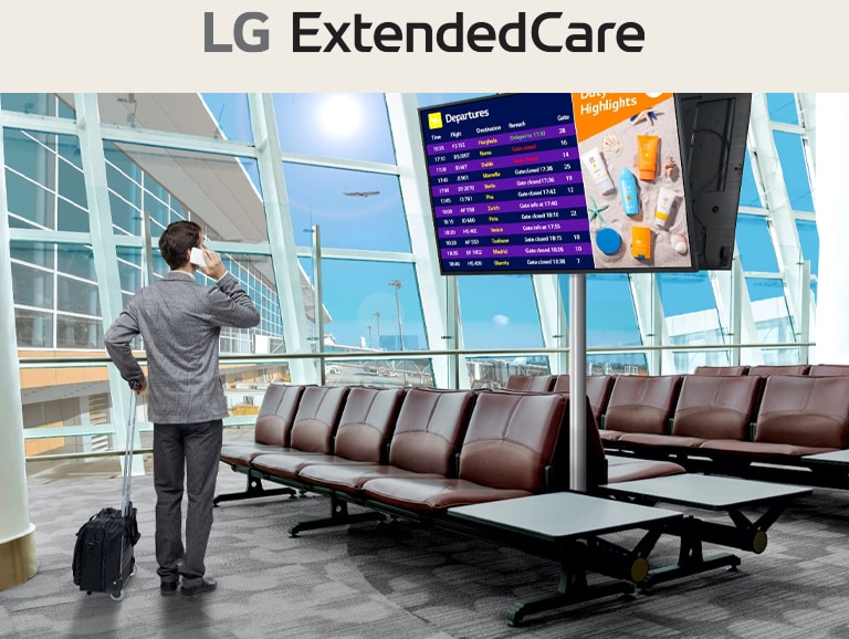A traveler stands in an airport lounge, checking his phone while looking at a digital departure board displaying flight schedules. The scene highlights the modern, efficient use of signage for real-time updates.