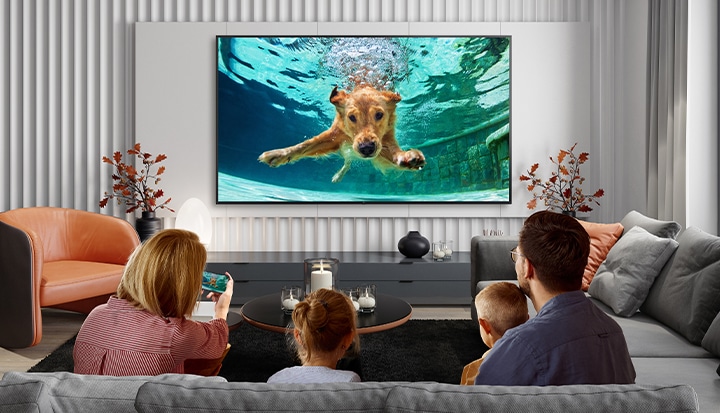 The image is showing a family streaming video content from their smartphone to the hotel TV using the casting service provided by LG Pro:Centric Cloud.