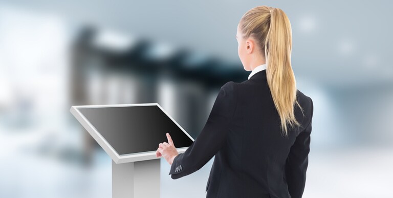 A woman is touching a lower installed TNF3K. The TNF3K is installed tilted toward the woman so she can see the display content well.