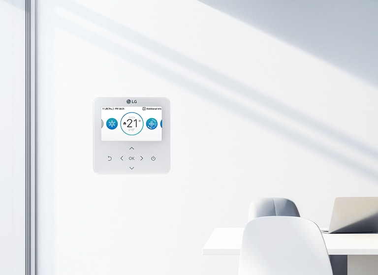 The image shows a clean office space with an LG control panel mounted on a white wall. The control panel displays a temperature setting of '21°C.