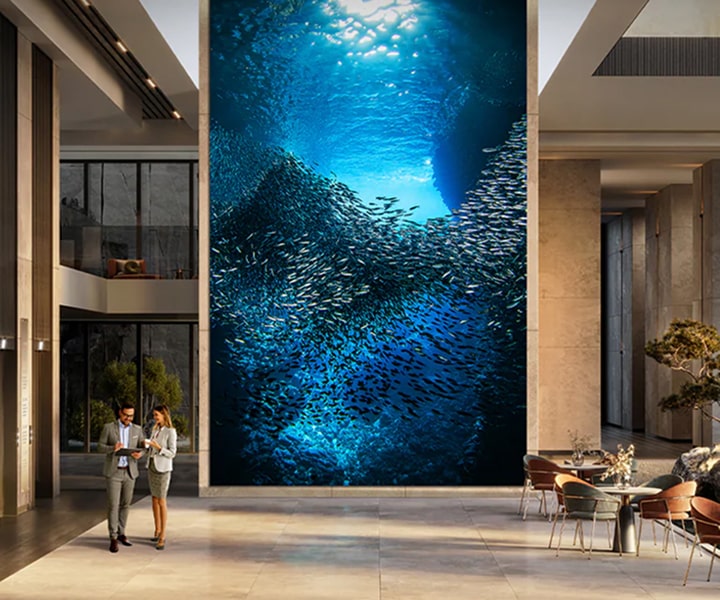 LG MAGNIT Micro LED display installed in a luxurious lobby, showcasing an immersive underwater scene with a school of fish, delivering stunning visual impact and premium viewing experience.