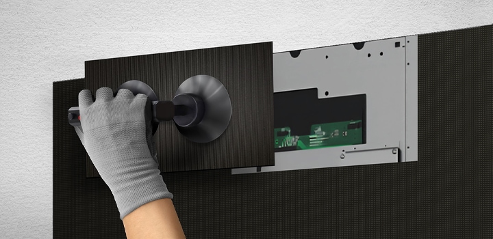 A person replaces one of the LED modules from the front using the provided suction cup tool.