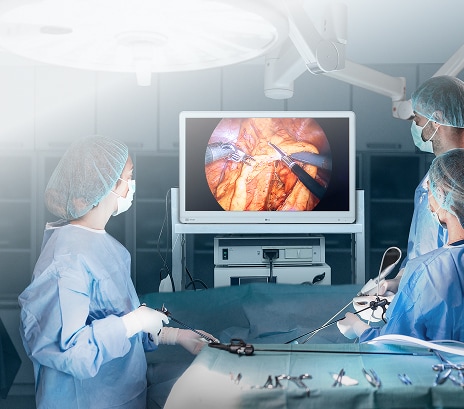 Surgical team using LG medical-grade monitor during minimally invasive operation with real-time imaging display.