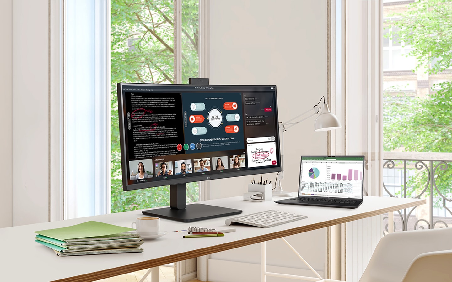 Home office desk with monitor, laptop, and books by the window