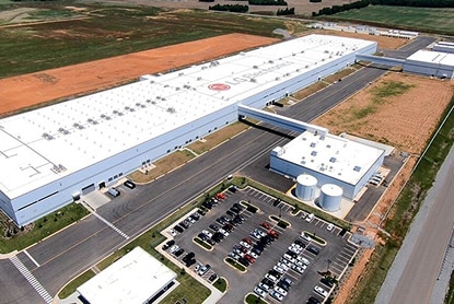 Large LG manufacturing plant with parking lot and cylindrical tanks, aerial view